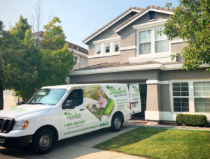 A white Do it Green van parked in front of a house.