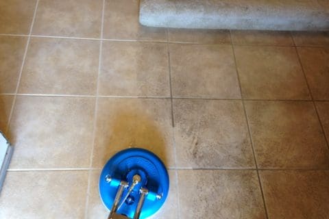 A tile floor being cleaned with a blue mop.